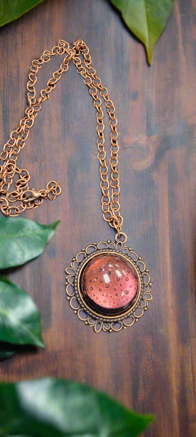 Expertly crafted by SB, this handmade resin necklace features a stunning copper pendant that resembles a glowing moon. Adorn yourself with this unique and intricate piece for a touch of celestial elegance.