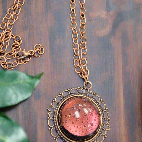 Expertly crafted by SB, this handmade resin necklace features a stunning copper pendant that resembles a glowing moon. Adorn yourself with this unique and intricate piece for a touch of celestial elegance.