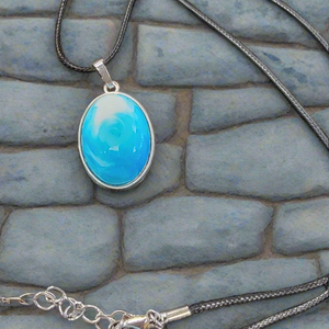This handmade resin blue and white pendant by SB features a unique swirling design, reminiscent of ocean waves. Each piece is carefully crafted to capture the beauty of sea colors, making it a one-of-a-kind accessory. Add a touch of elegance and nature to your outfit with this stunning necklace.