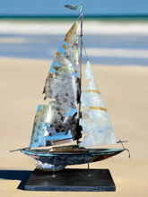 This stunning home decor piece features capiz shell inlay, adding a touch of elegance and coastal charm to any space. The aluminum and capiz shell torn sailboat standing is expertly crafted and perfect for those who appreciate unique and high-quality design. Add a coastal touch to your home with this magnificent piece.18 tall x 13 wide

